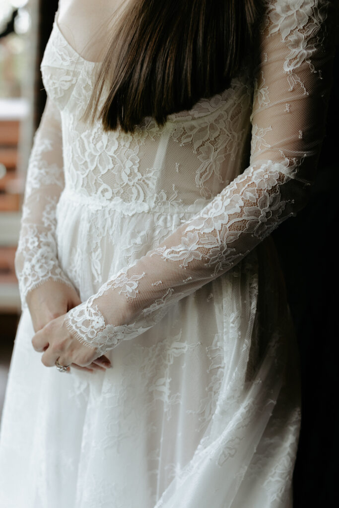 A woman wearing lace sleeved wedding dress. 