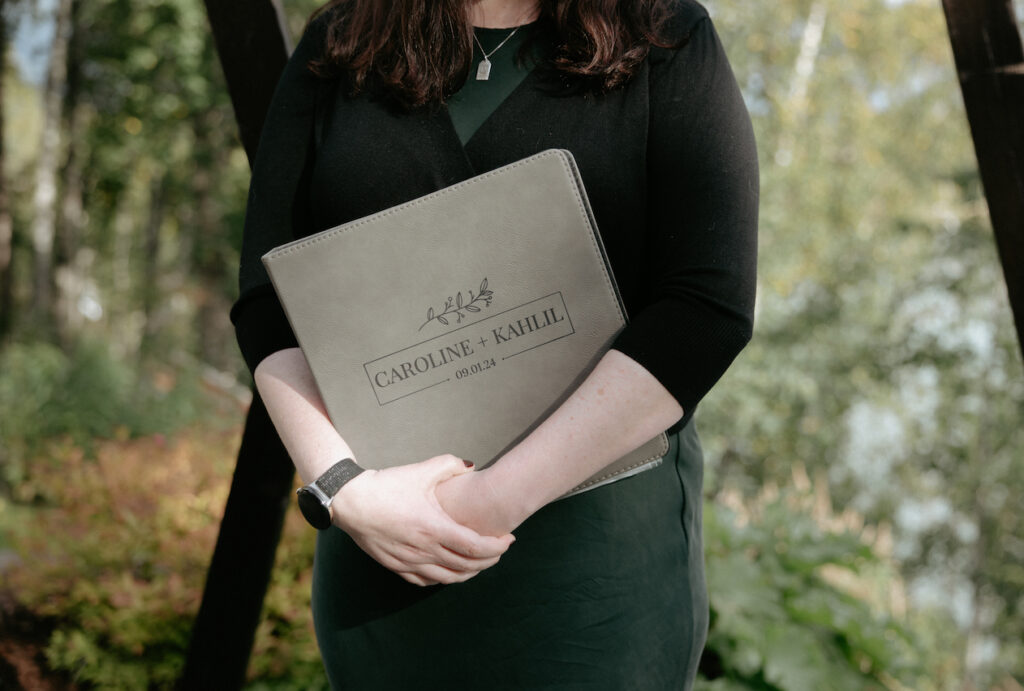 Woman holding a book with the couples name on it.