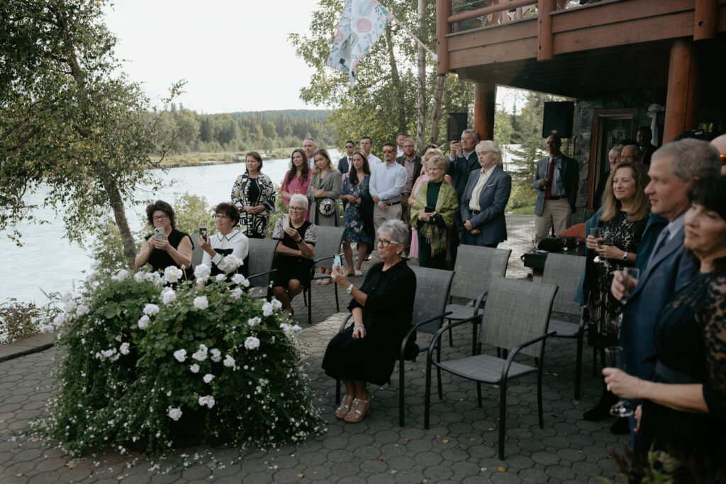 Family and friends sitting and standing while the couple exchanges vows. 