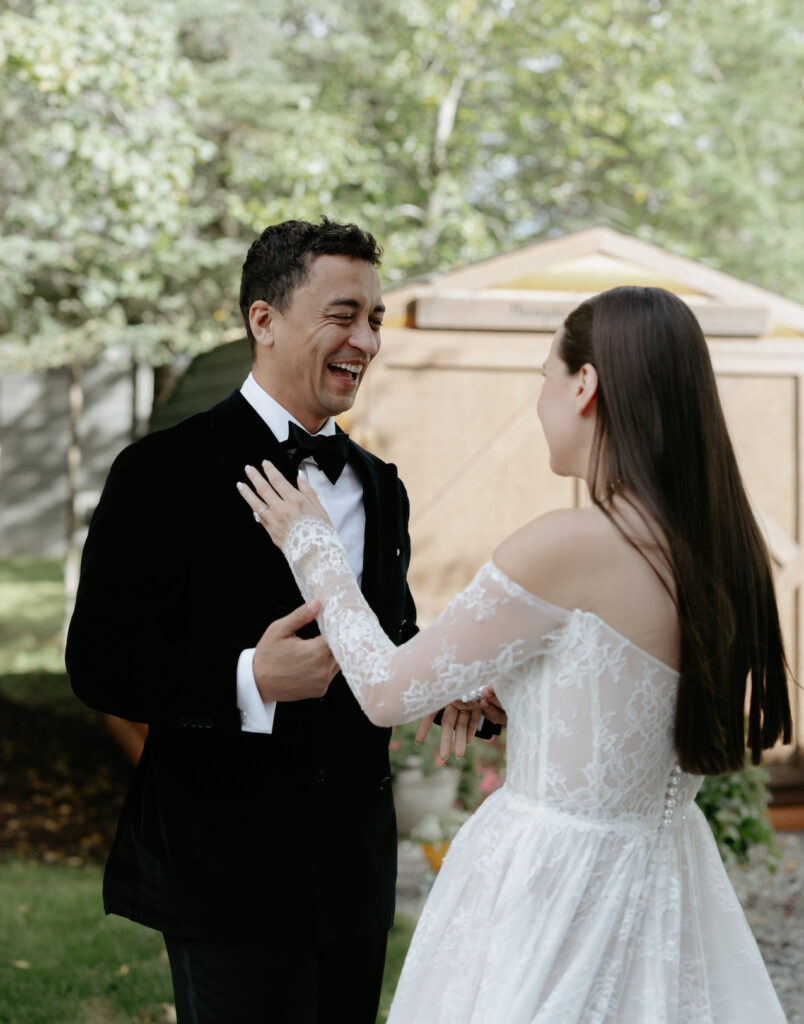 A man wearing a black suit and smiling as he see's his fiance for the first time. 