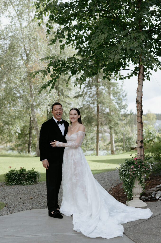 A couple holding onto one another while standing under a tree. 