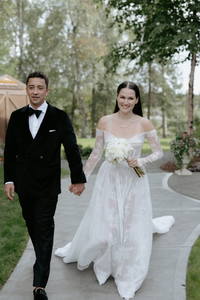 A couple holding hands and walking along a stone path. 