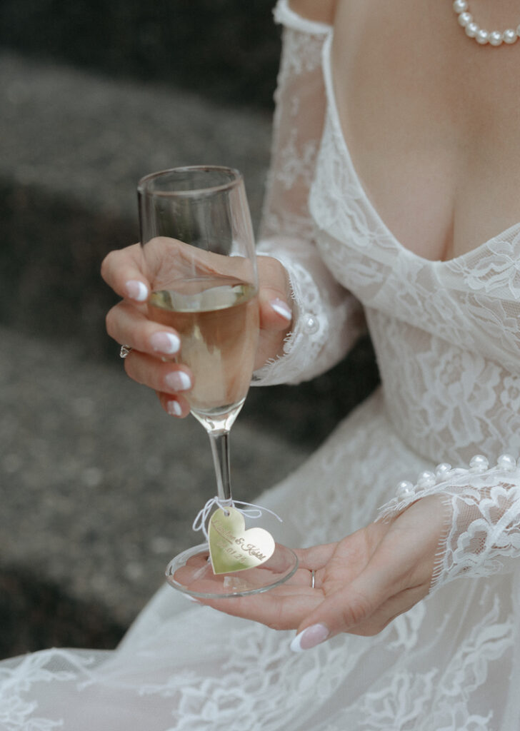 A woman holding a glass of champagne with a heart embellishment attached. 