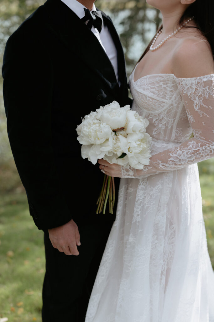 A woman holding a white bouquet of long stem flowers. 