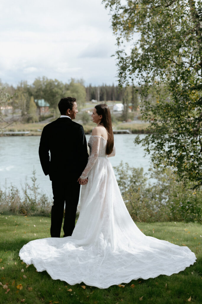 A couple holding hands and looking at one another while next to a river. 