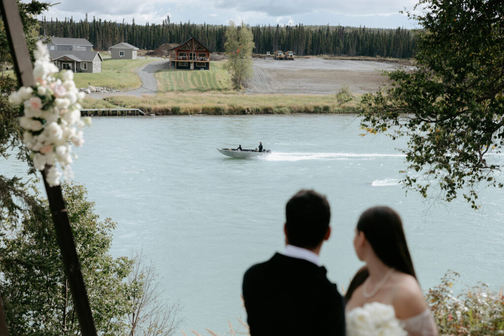 A couple looking out to the river as a boat passes by. 