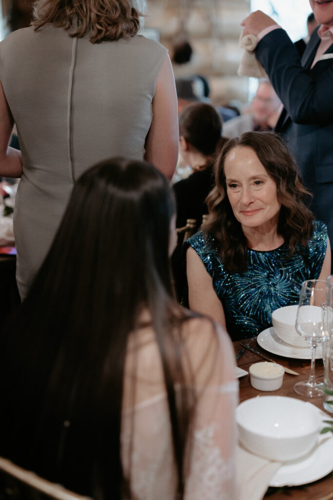 A woman talking to the bride who is wearing a white dress.