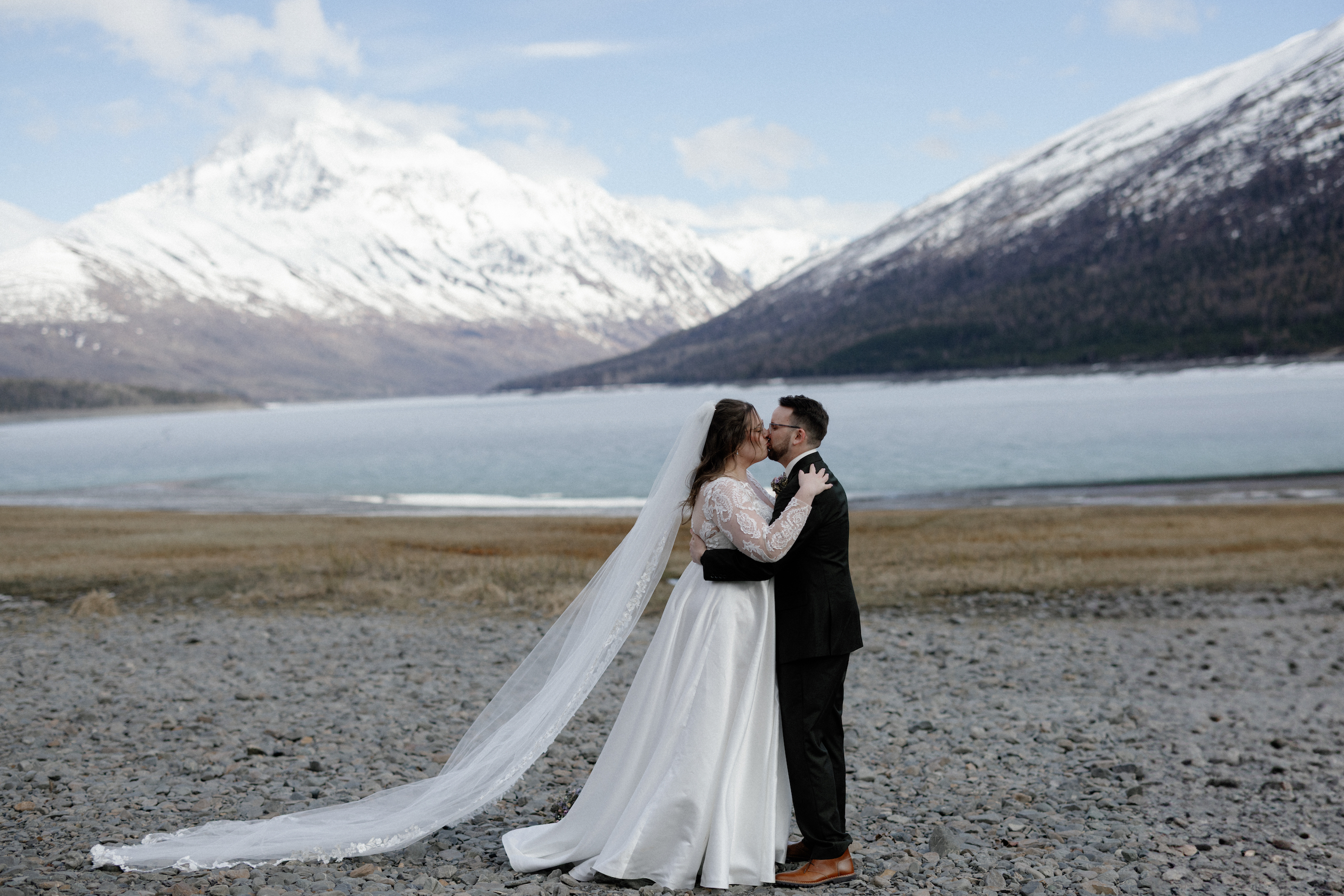 A couple kissing next to Eklutna Lake after their wedding ceremony. 