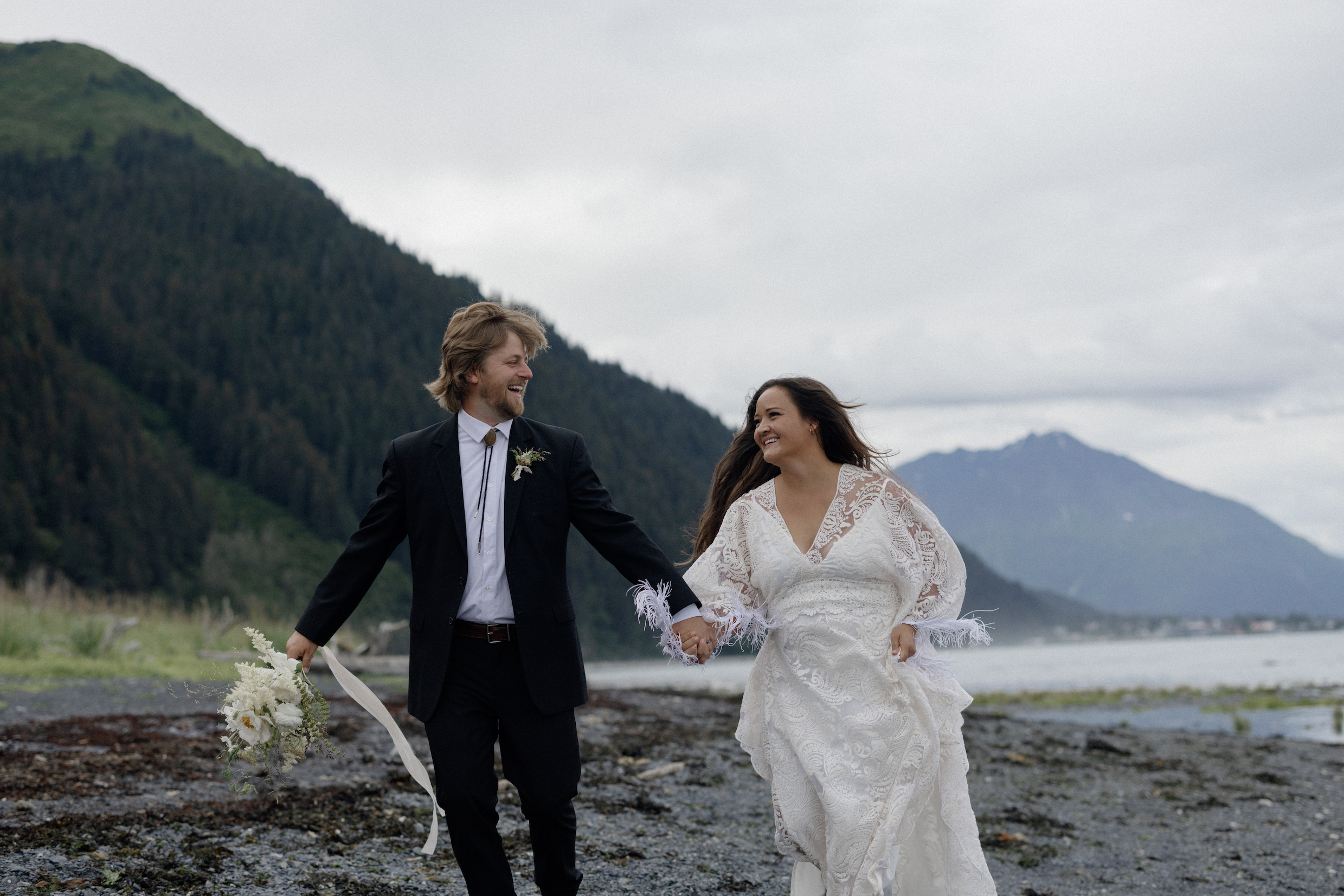 A couple holding hands and running during their rainy wedding in Alaska. 