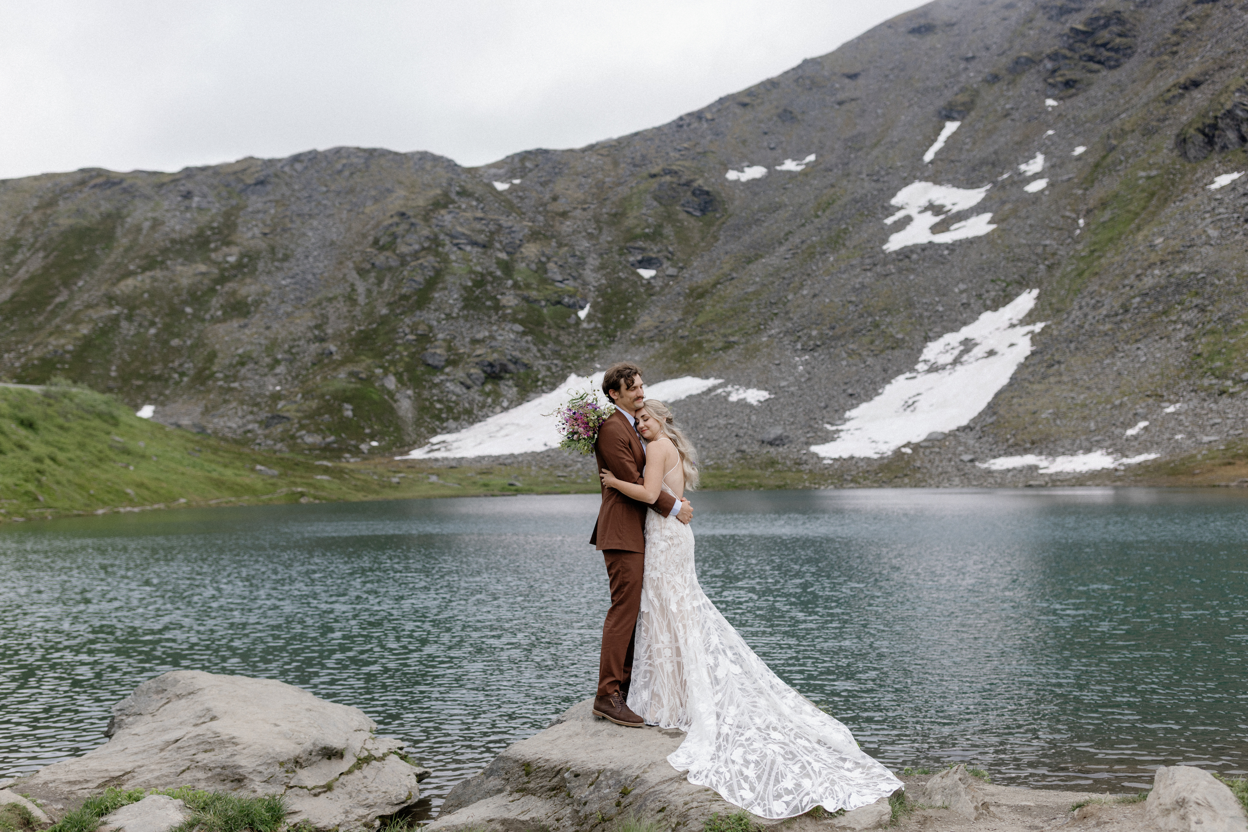 A couple holding onto one another during their outdoor wedding in the mountains. 