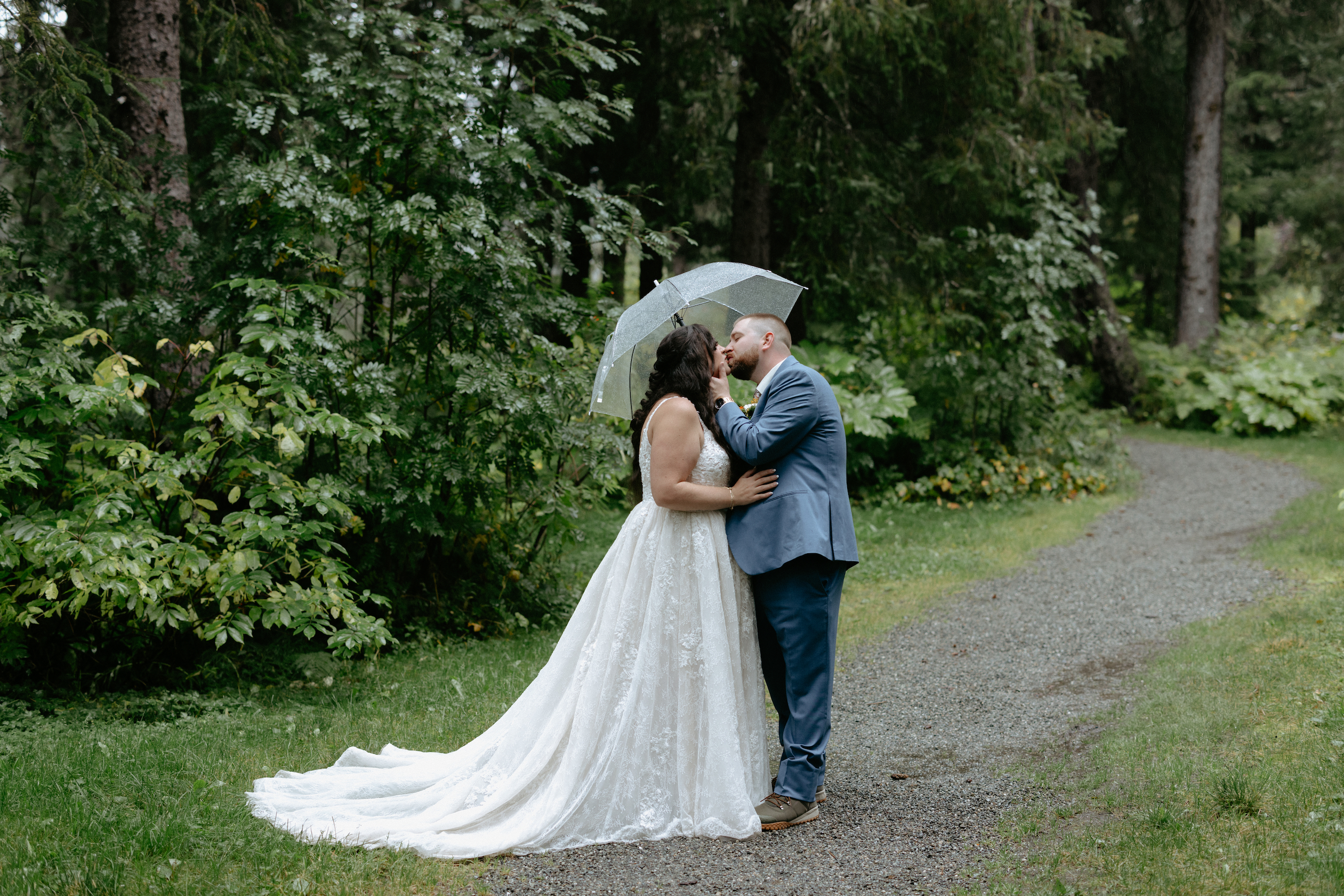 A couple kissing under a umbrella for portraits in Girdwood. 