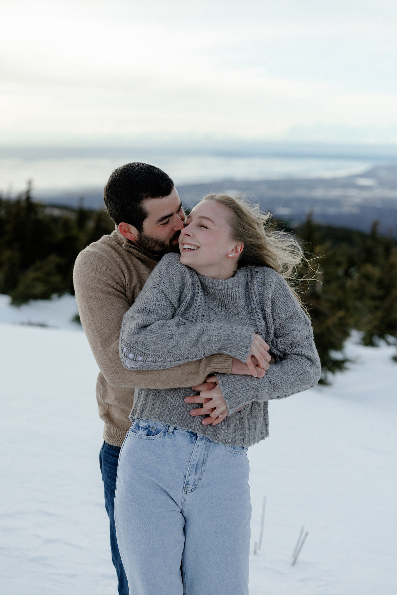 A man wrapping his arms around a woman while standing in the snow.