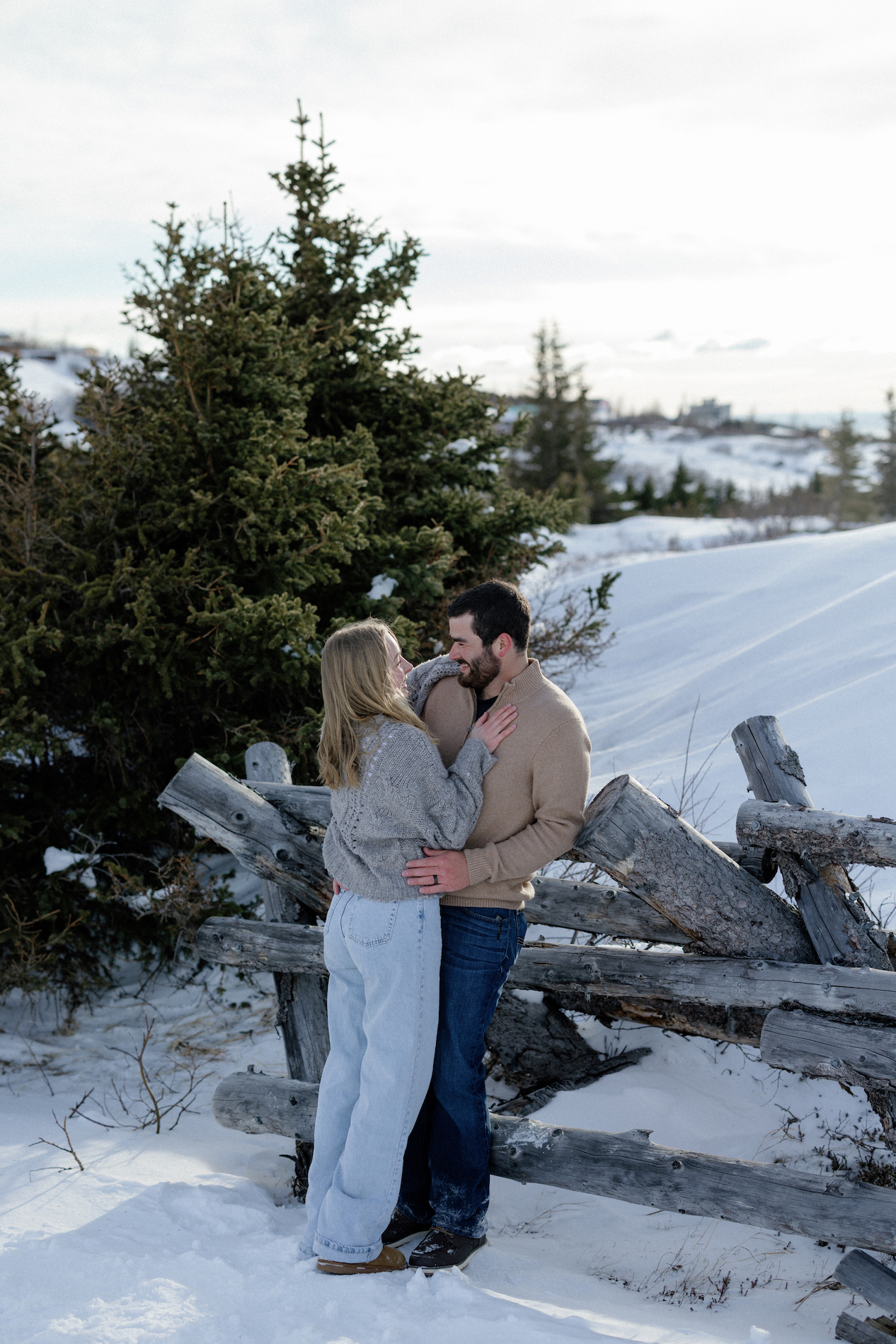 A couple snuggled up next to a fence during an engagement session at Glenn Alps.