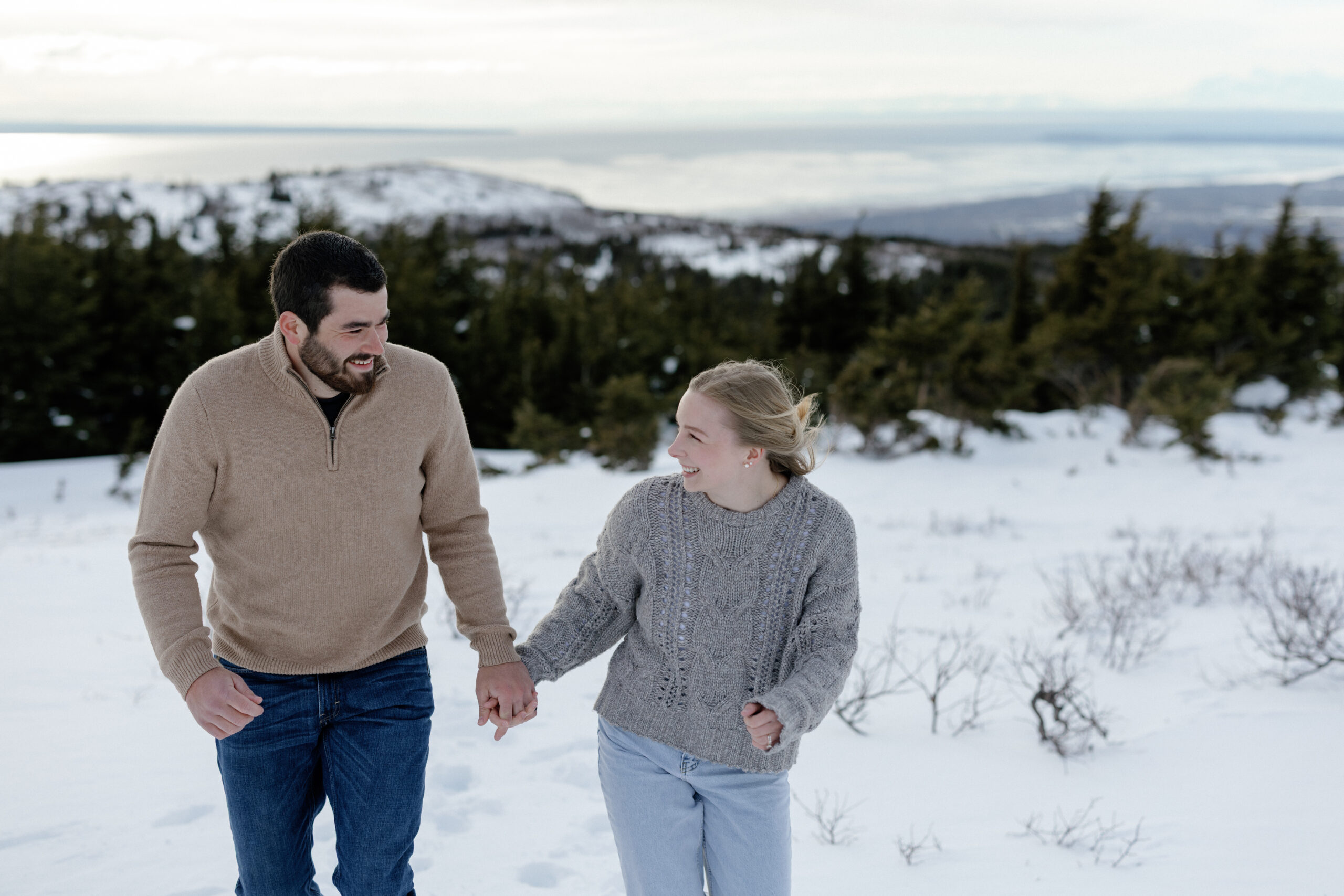 A couple holding hands and walking on the snow.