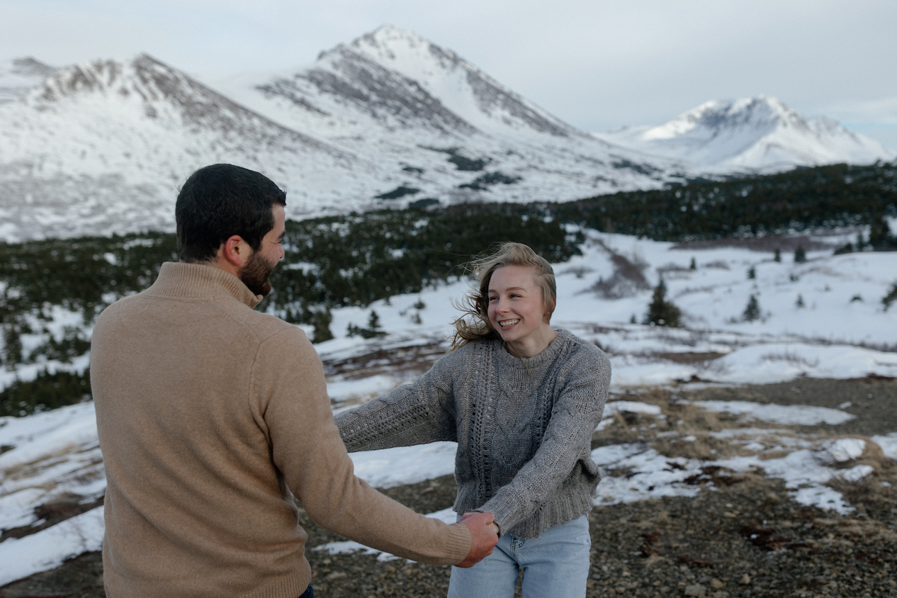 A couple holding hands and running around while taking engagement photos in Alaska.