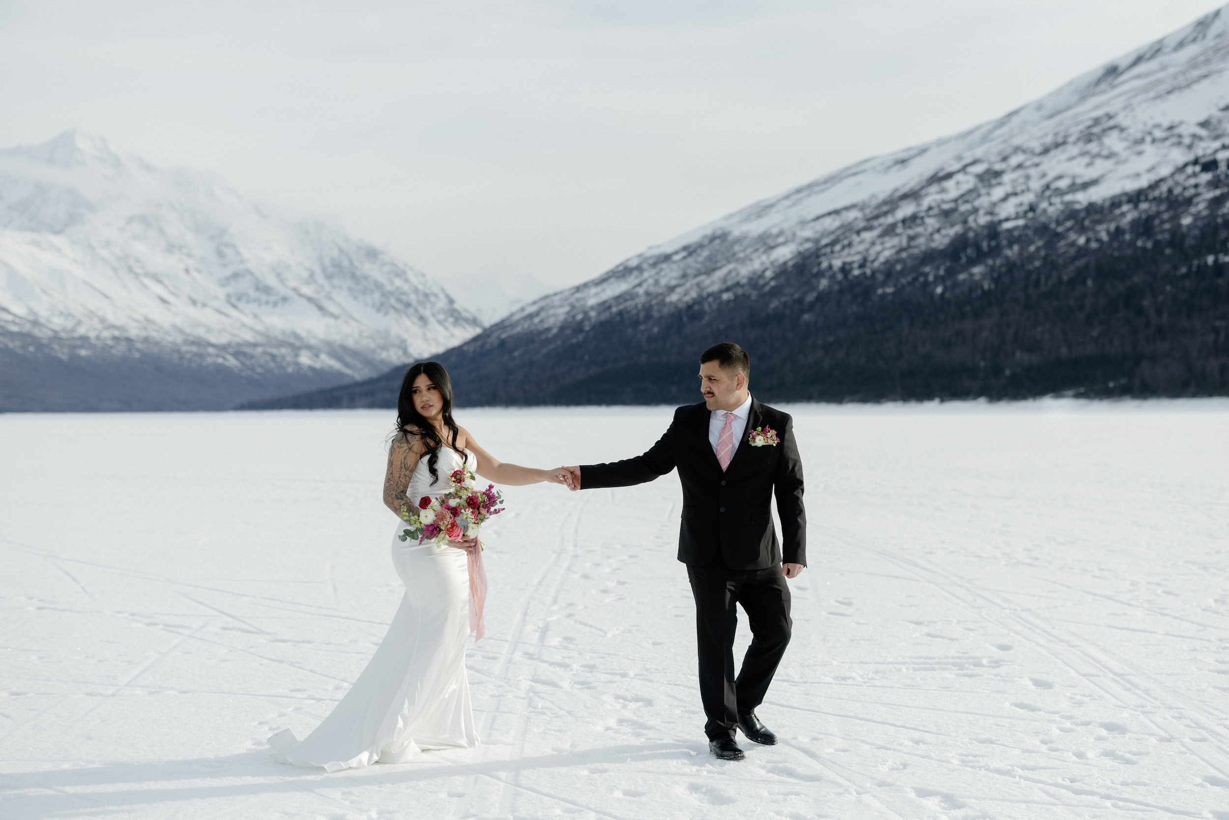 A couple holding hands and walking on a frozen lake.