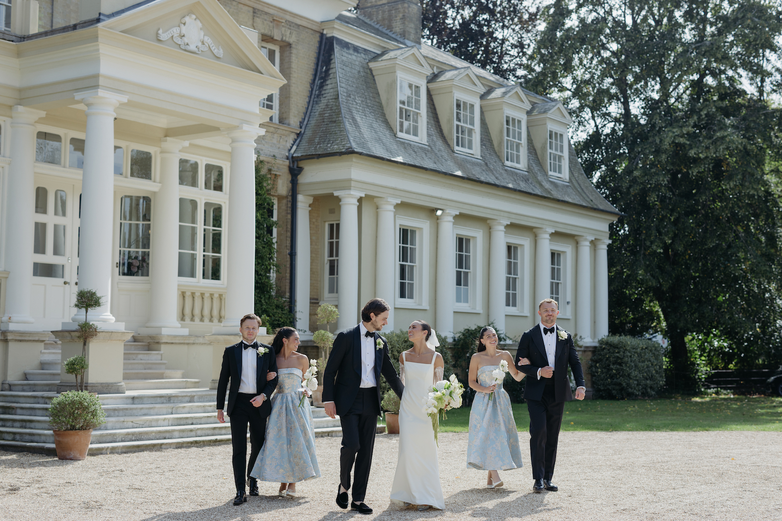 A bridal party walking in front of Pylewell Park while wearing wedding attire.