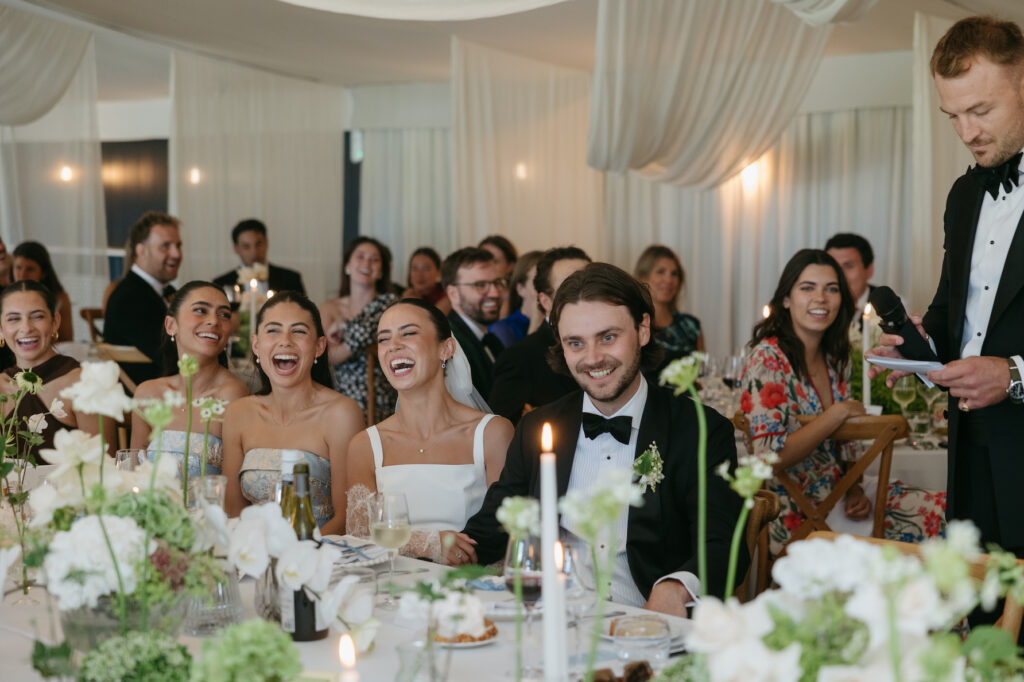 A couple sitting together and laughing during a wedding reception.