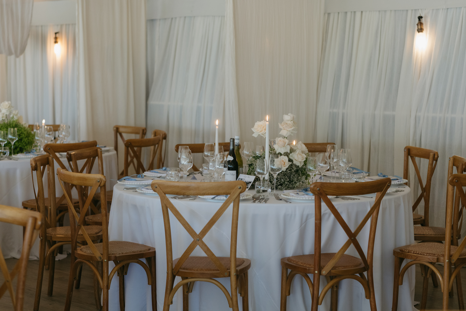 A white table with white and green flowers and candles.