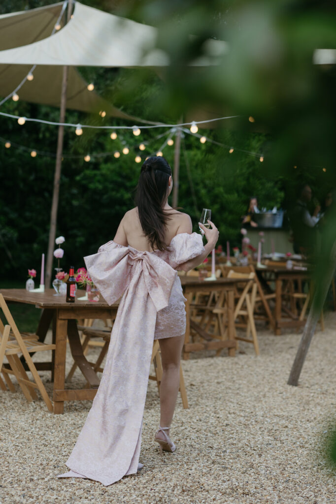 A woman wearing a pink dress with a bow during a welcome party at Pylewell Park.