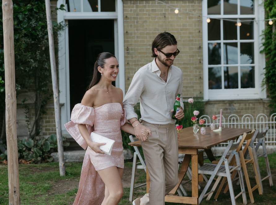 A couple holding hands and greeting guests.