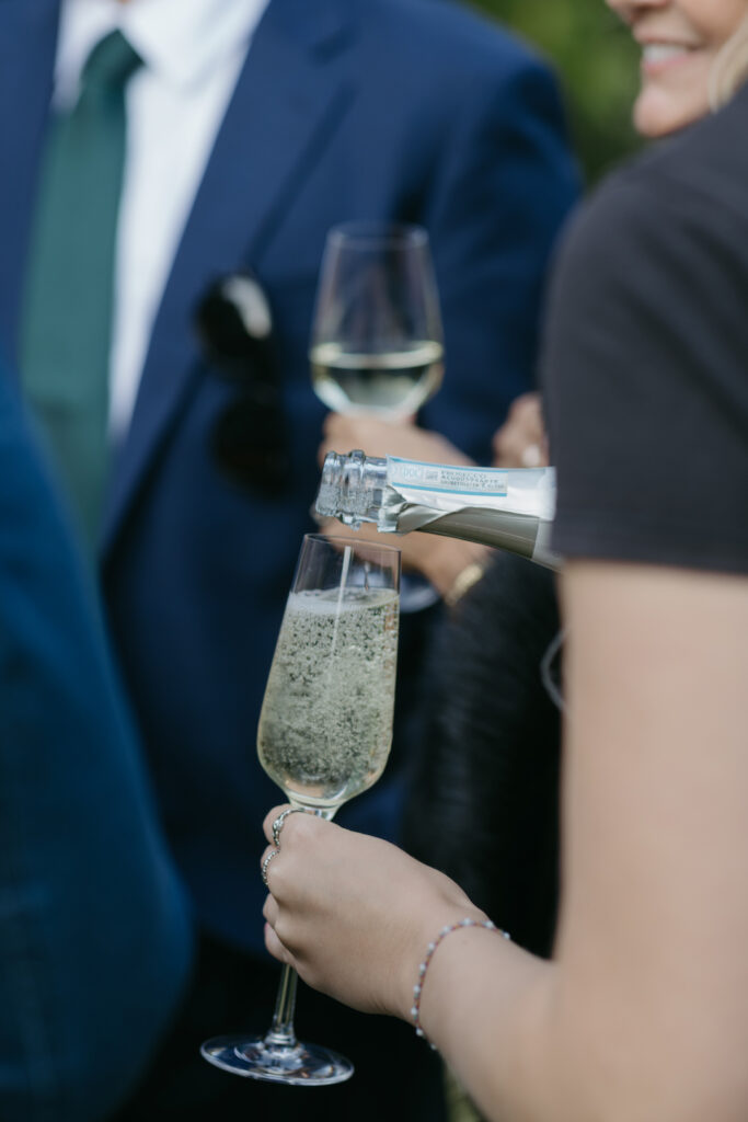 A woman pouring a glass of champagne for a guest a wedding at Pylewell Park.